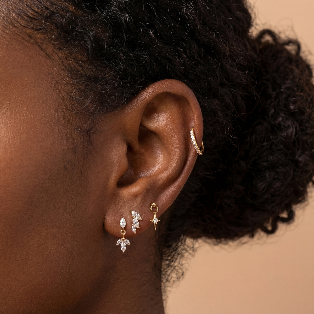 Close-up of an ear wearing gold and diamond earrings with a blurred background