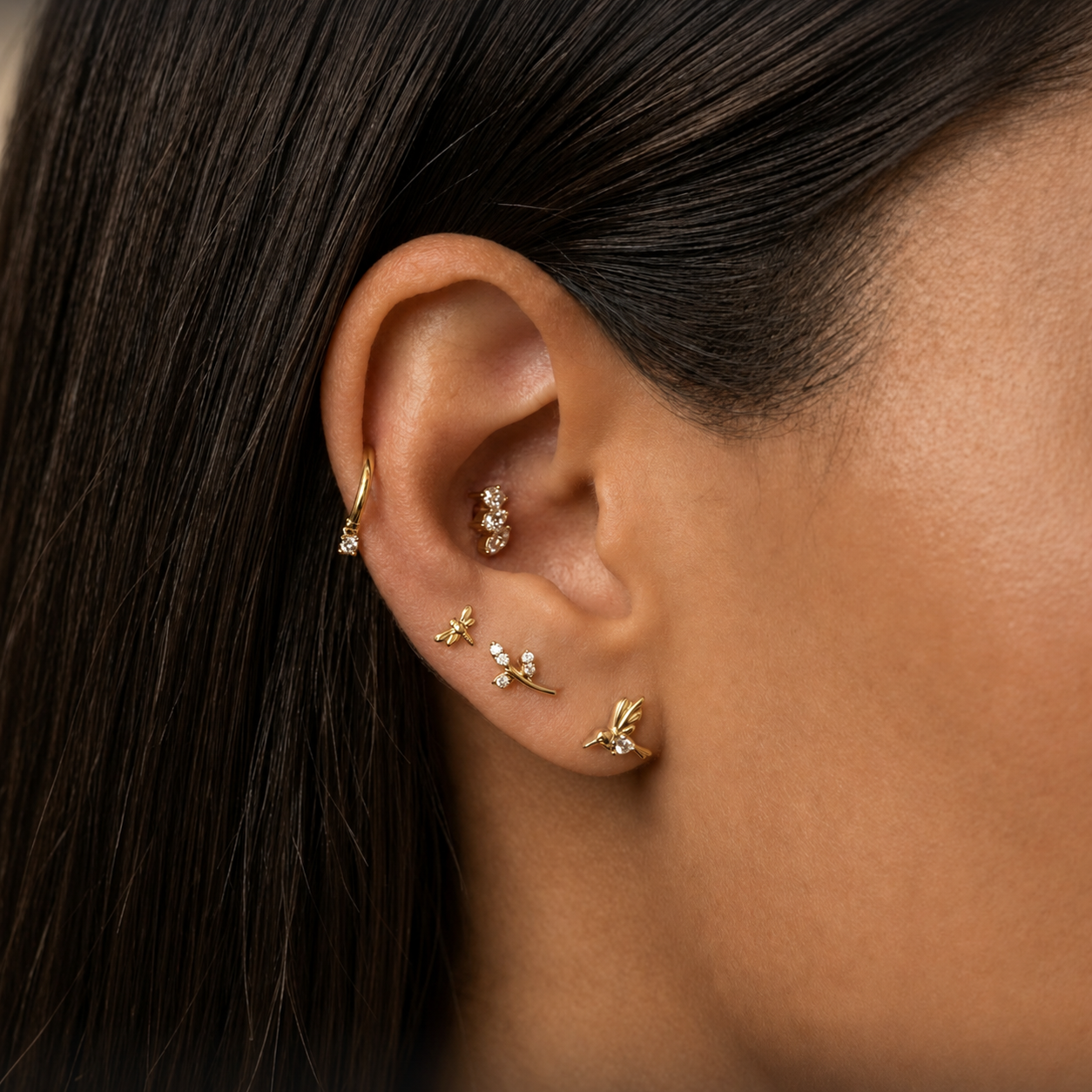 close up van oor met gouden  sieraden en zwart haar