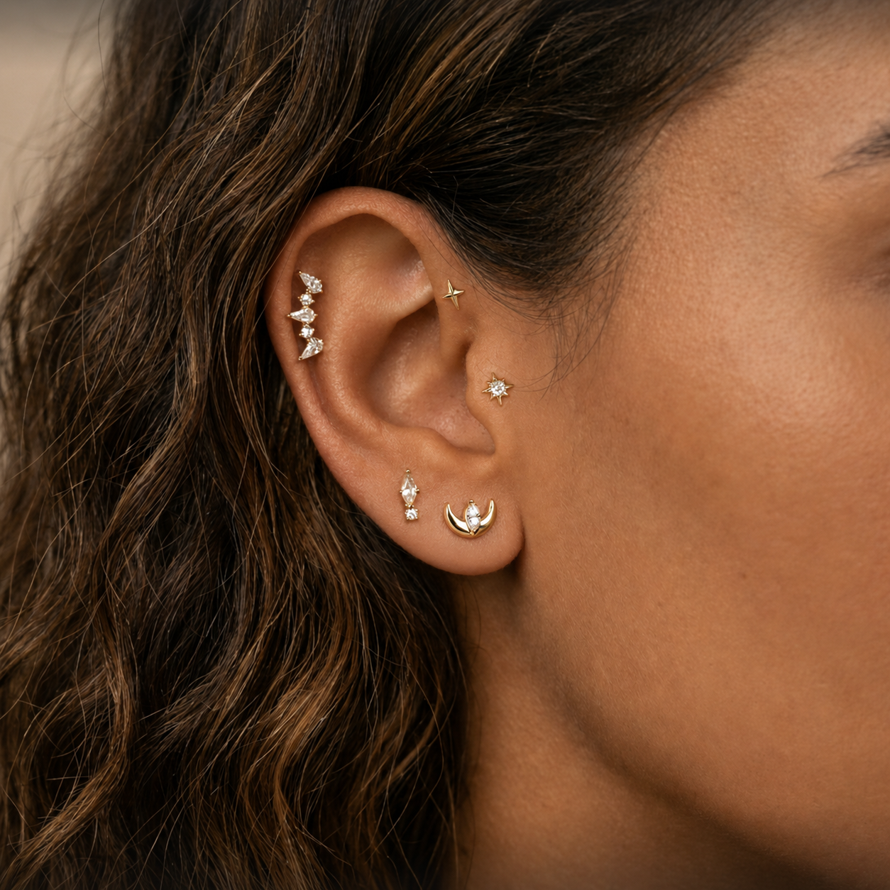 close up oor met gouden sieraden en bruin haar